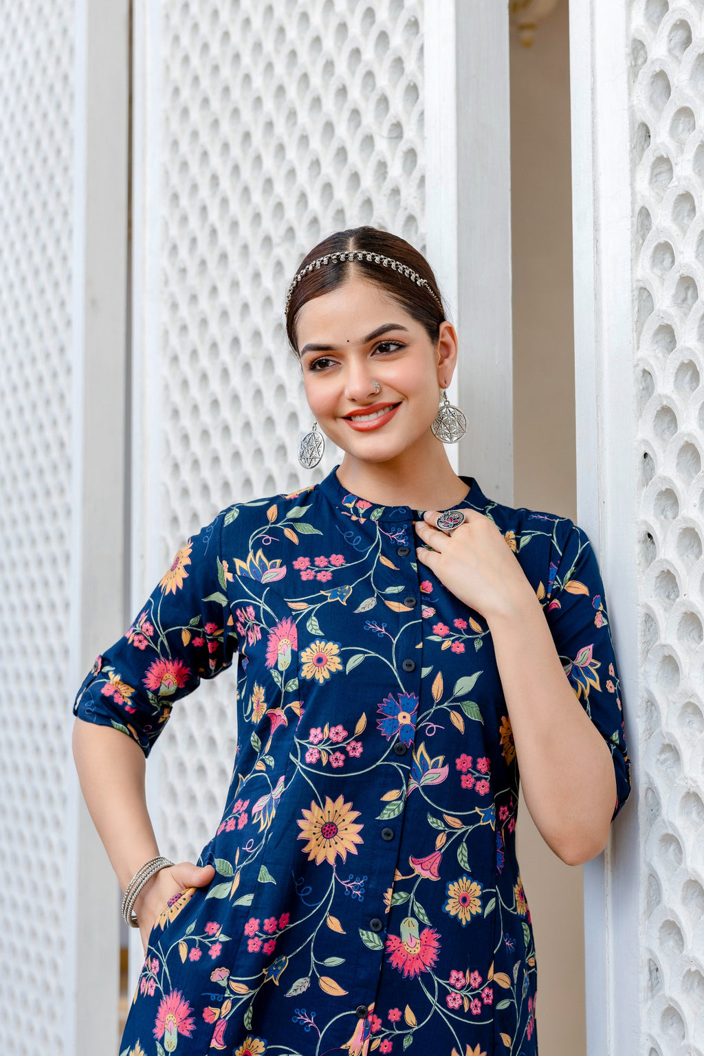 Woman wearing a navy blue floral dress against a white decorative background